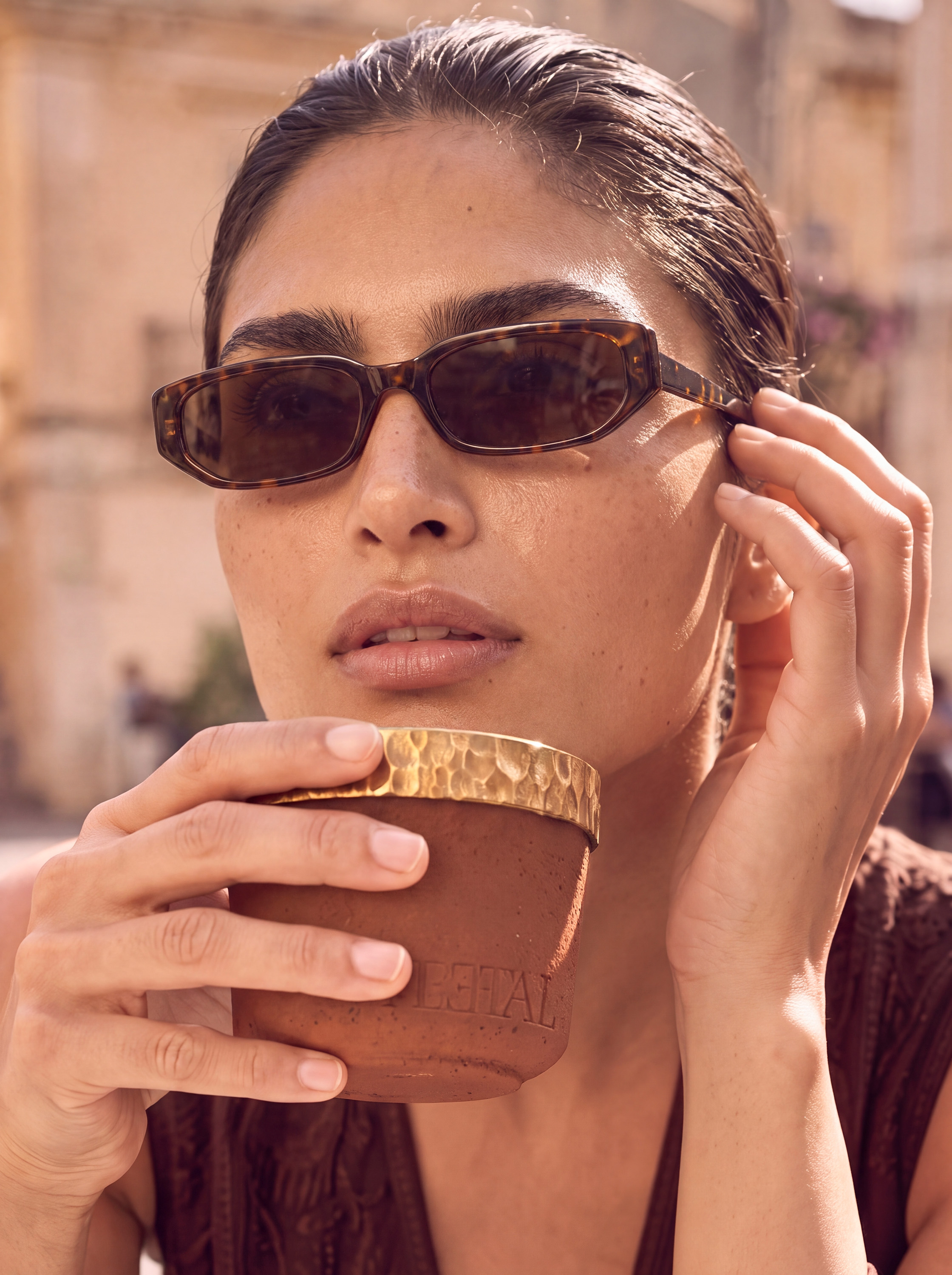 Beauty close-up — model holding PEETAL, brass rim prominent